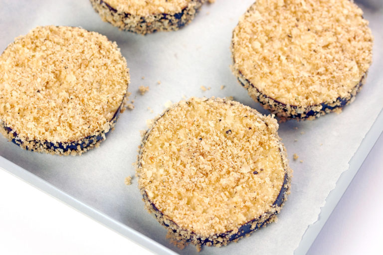 Breaded eggplants on a silver cooking sheet.