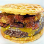 Chaffle loaded with western bacon cheeseburger toppings like onion rings, BBQ sauce and cheese