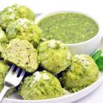 Pesto Meatballs sitting on a white plate with pesto dipping sauce. Made with ground chicken or turkey.