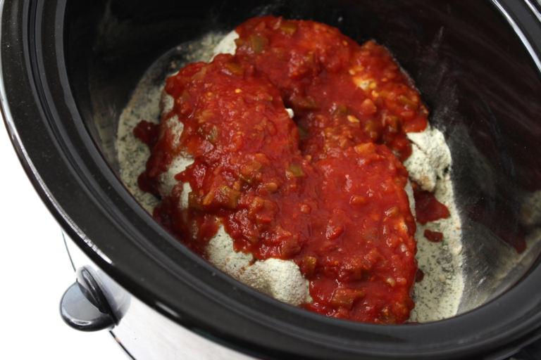 Chicken in black slow cooker topped with salsa