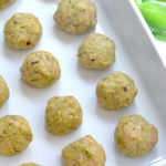 Raw Pesto Meatballs sitting on a baking sheet.