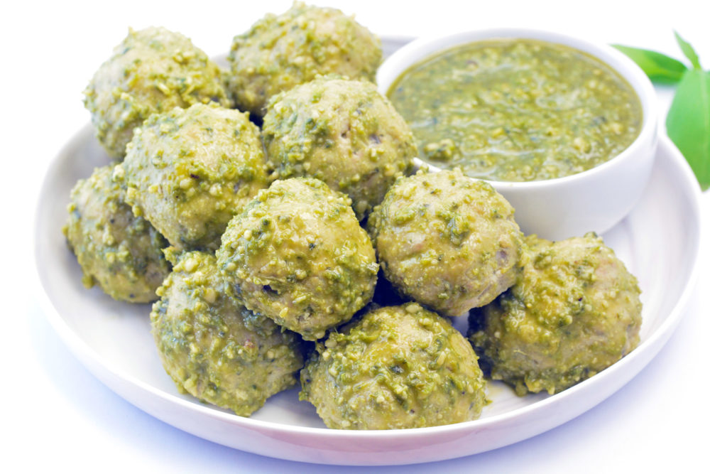 Pesto Meatballs sitting on a white plate with pesto dipping sauce. Made with ground chicken or turkey.