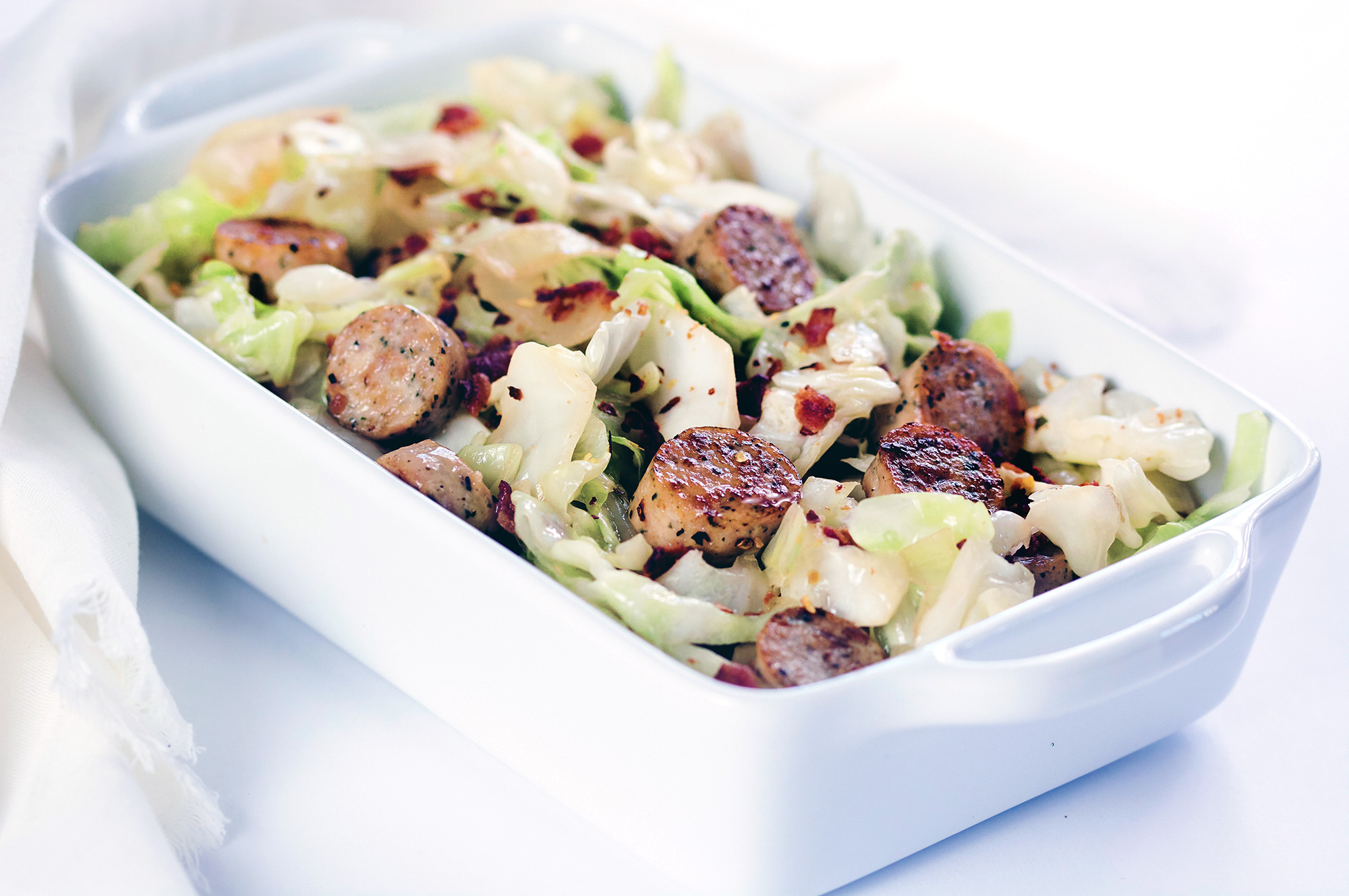 Close up picture of Sautéed Cabbage with bacon, sausage and onions in a skillet.