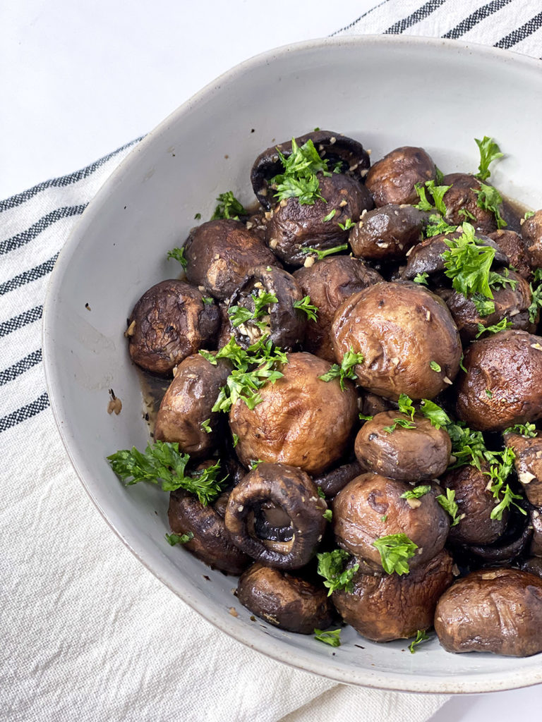 Oven Roasted Garlic Mushrooms in a white bowl topped with parsley.