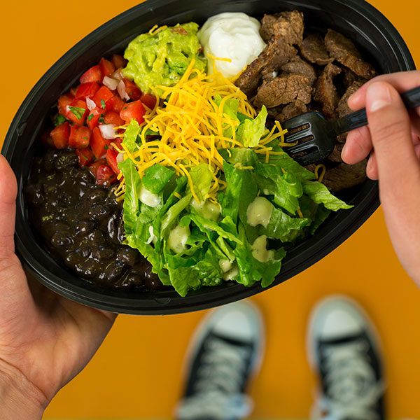 Picture of a Taco Bell Power Bowl with lettuce, cheese, steak and guacamole.