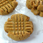 Baked Keto Peanut Butter cookies on parchament paper and a silver baking sheet.