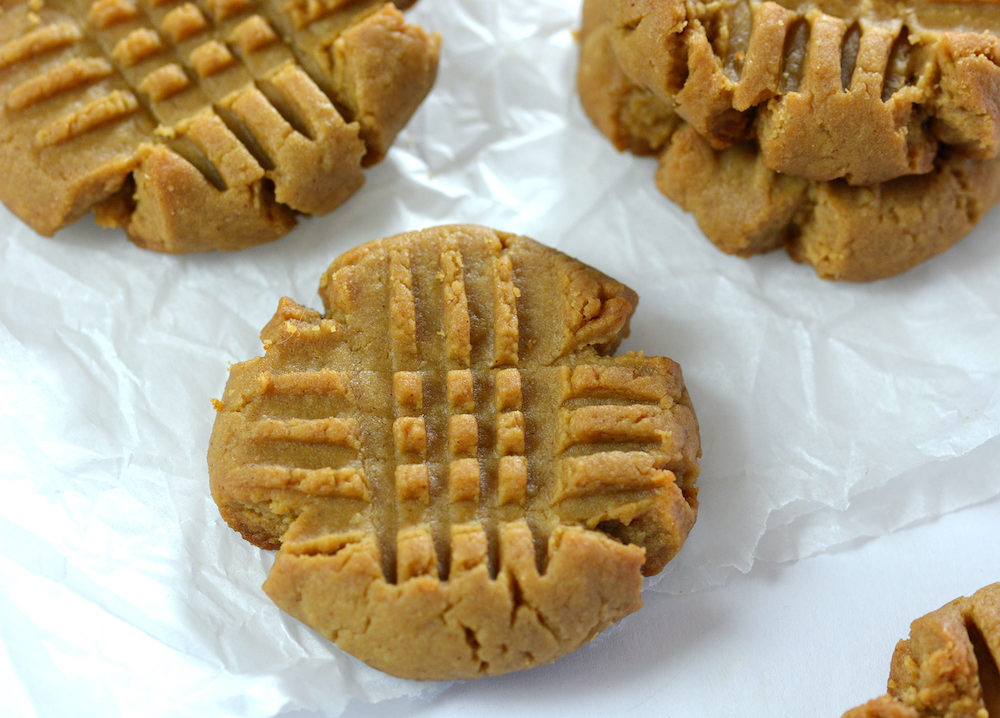 Baked Keto Peanut Butter cookies on parchament paper and a silver baking sheet.