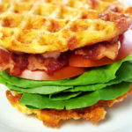 Picture of a BLT Chaffle Recipe on a white plate. The chaffle is loaded with lettuce, bacon, tomato and mayo.