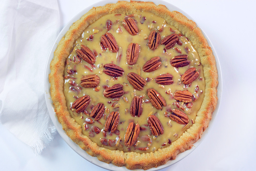 round pecan pie topped with pecan halves in a circular design.