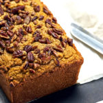 Loaf of Keto Pumpkin bread on a black cutting board and bread knife.