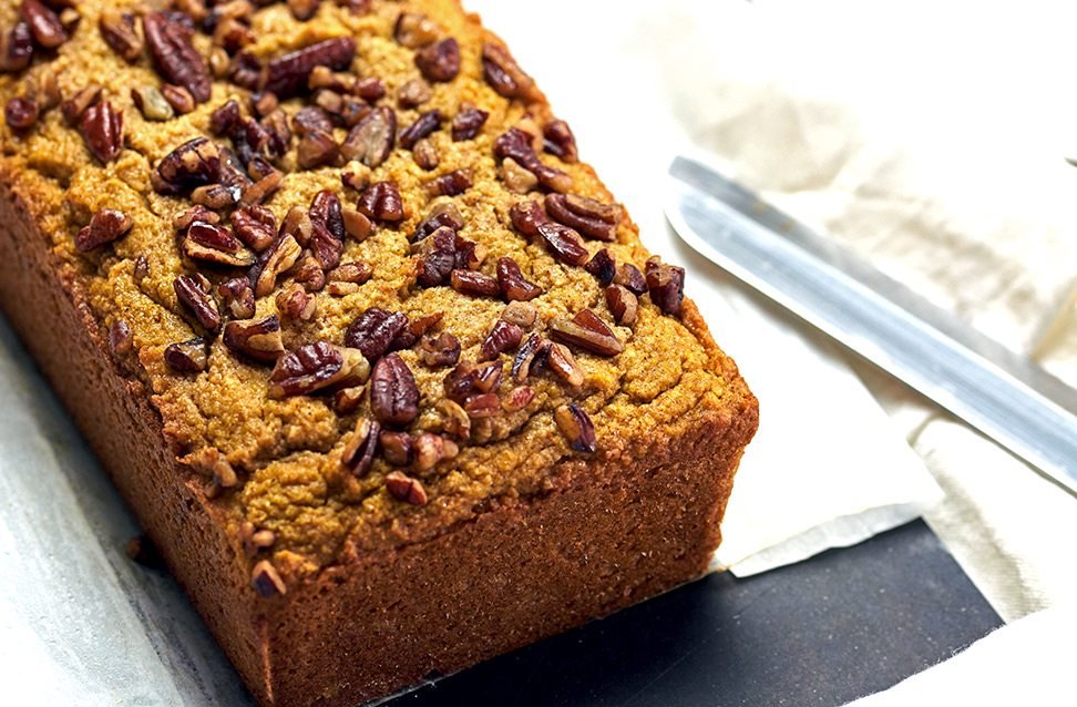 Loaf of Keto Pumpkin bread on a black cutting board and bread knife.