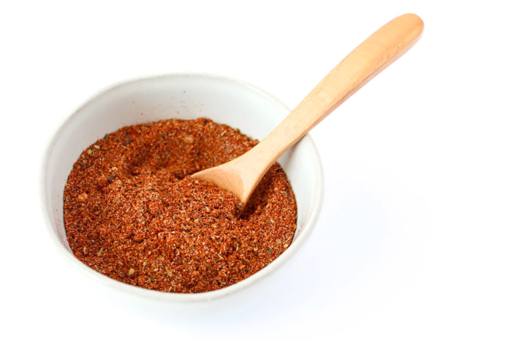 Taco seasoning in white bowl with wooden spoon placed inside