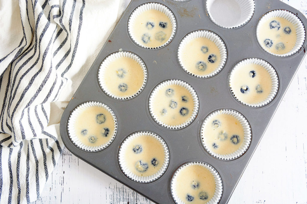 Overhead shot of uncooked low carb blueberry muffin mix in muffin tins.